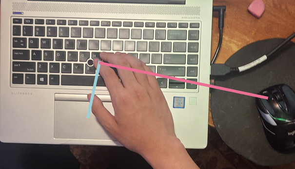 Visual diagram from sky view with two lines showing the distance between the hand position in the keyboard to the touchpad and the mouse. The line to the mouse is a longer distance compared to the line to the touchpad.